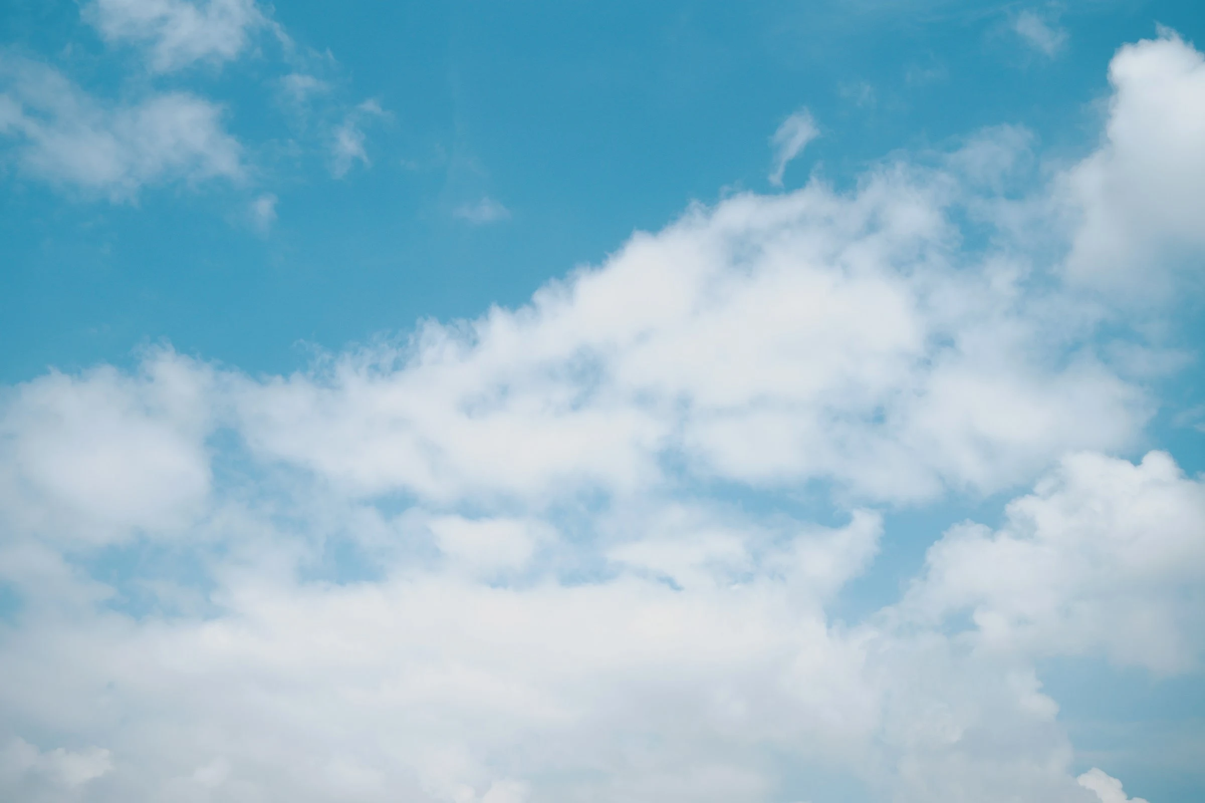 Soft sunlit clouds opening onto a calm blue sky